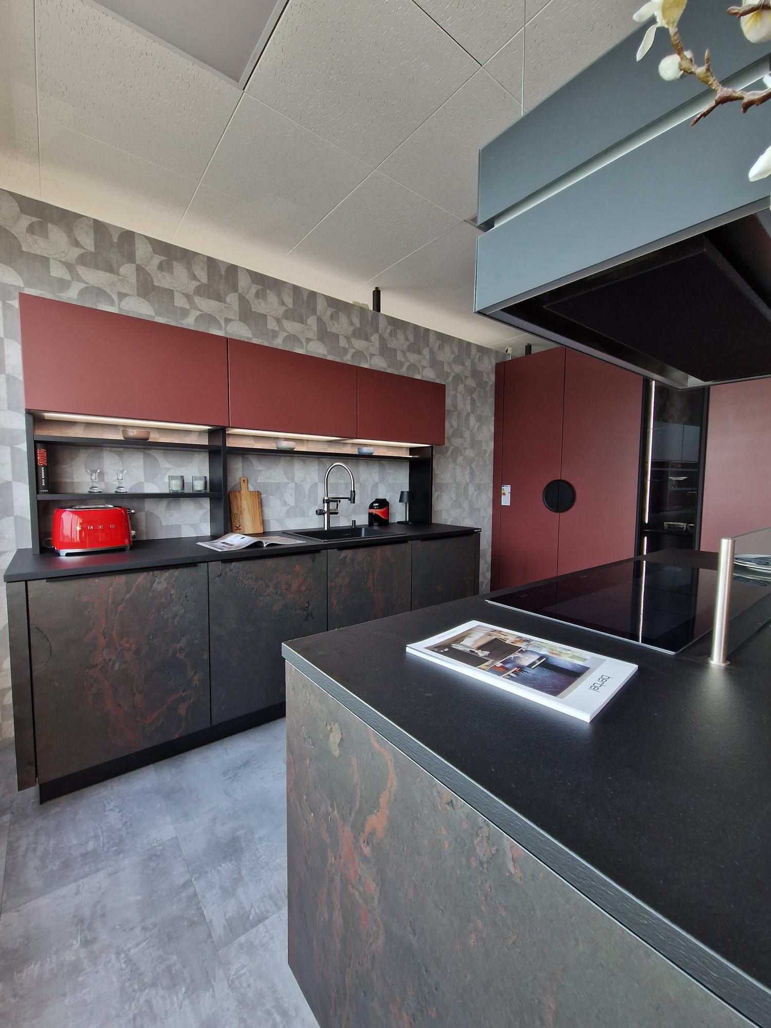 Genießen Sie ein Höchstmaß an Komfort und Stil in unserer Nolte Neo Einbau-Musterküche, die nicht nur mit einer Blanco Drink.hot Evol-S Pro für unmittelbar verfügbares, heißes Wasser, sondern auch mit eleganten Fronten in Schiefer-Schwarz Rosato und Henarot Softlack, einer Berbel Skyline Dunstabzugshaube und beleuchteten Hängeschränken mit elektrischer Öffnung ausgestattet ist.