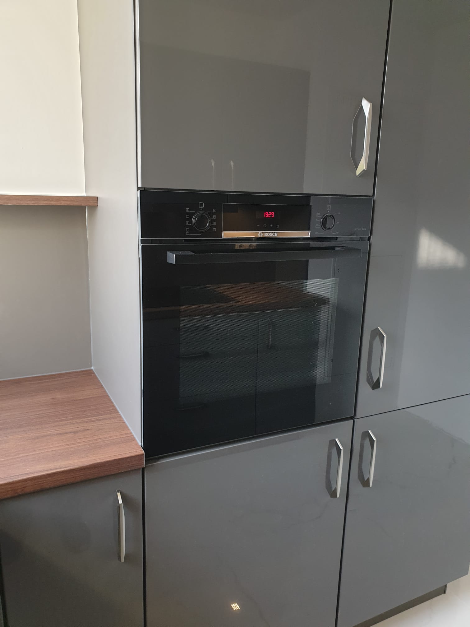 Hochglanzfronten in Schiefergrau kombiniert mit warmem Nussbaum – pflegeleichte Küche in klassischem Stil.