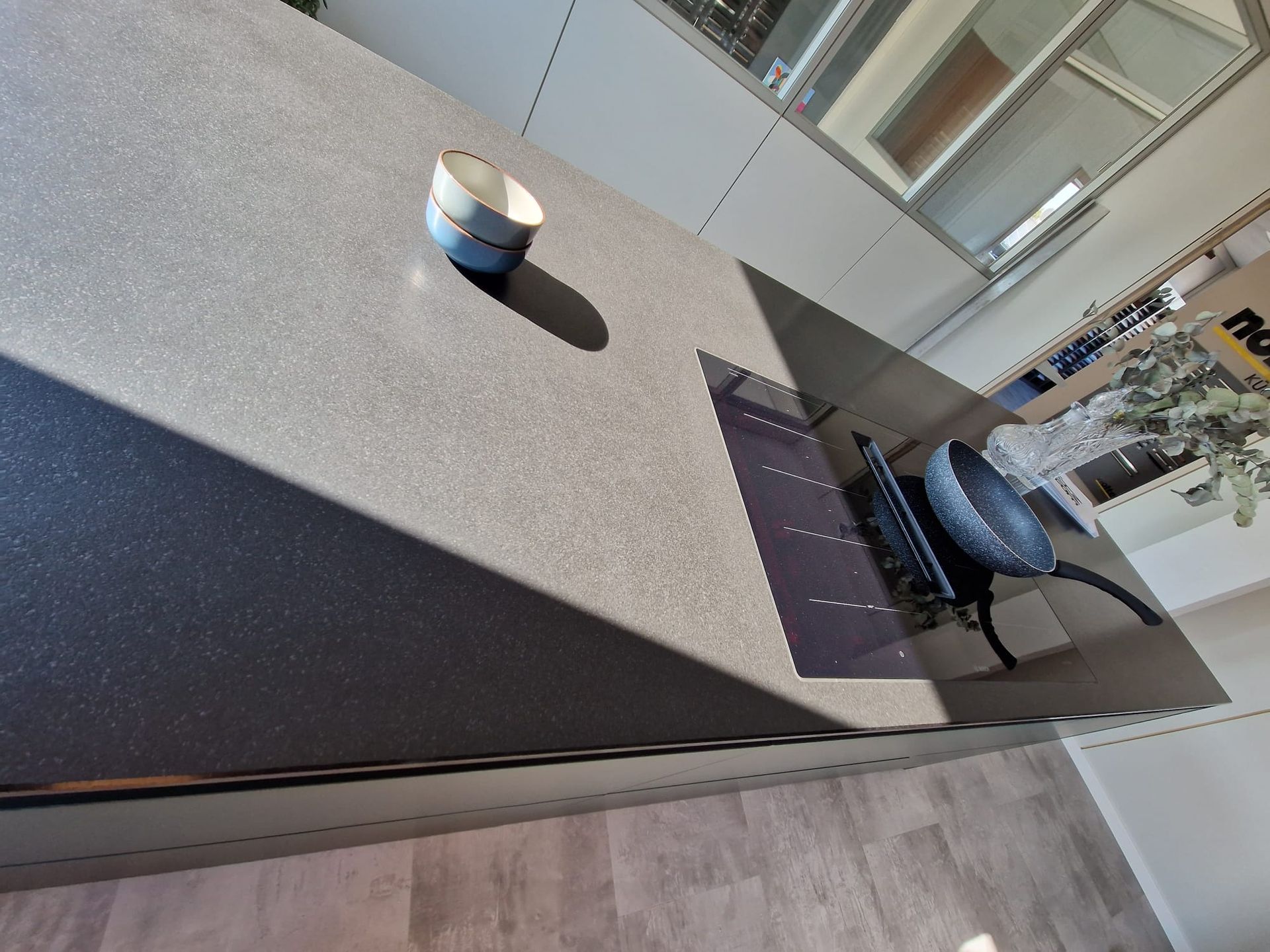 Entdecken Sie die vielen Vorteile einer Ballerina Musterküche, darunter das Rosso Nußbaum Furnier in Rillenoptik, die freistehende Insel mit Resopal-Front und die Natursteinarbeitsplatte, die nicht nur ästhetisch ansprechend sind, sondern auch höchste Qualität und Funktionalität bieten. Mit Ballerina Küchen sind Sonderanfertigungen möglich, um Ihre Küche maßgeschneidert zu gestalten.