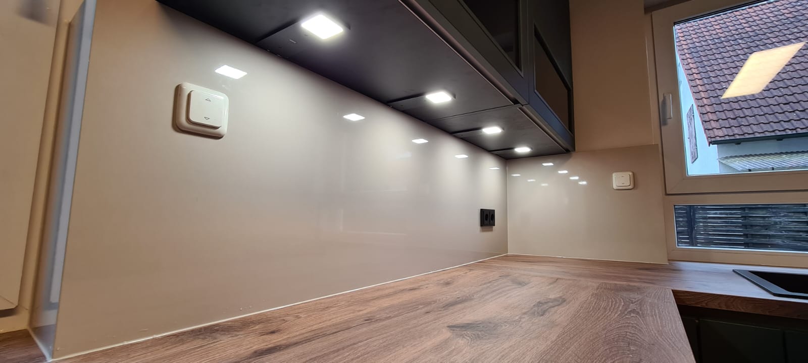 Das Bild zeigt eine ansprechende Nobilia Küche mit grifflosen Schränken, deren Schönheit durch die edlen EASYTOUCH 964 Mineralgrün ultramatten Fronten unterstrichen wird. Diese Küchenecke wurde mit viel Liebe zum Detail gestaltet und lädt dazu ein, den Tag mit einer entspannten Tasse Kaffee zu beginnen. Die Bosch accentline Einbaugeräte in stilvollem Schwarz passen perfekt zum Gesamtdesign und bieten innovative Funktionen für ein erstklassiges Kocherlebnis. Die geschickt platzierte LED-Beleuchtung setzt die Einbauküche gekonnt in Szene, betont ihre Eleganz und schafft eine warme, einladende Atmosphäre, die zum Verweilen einlädt.