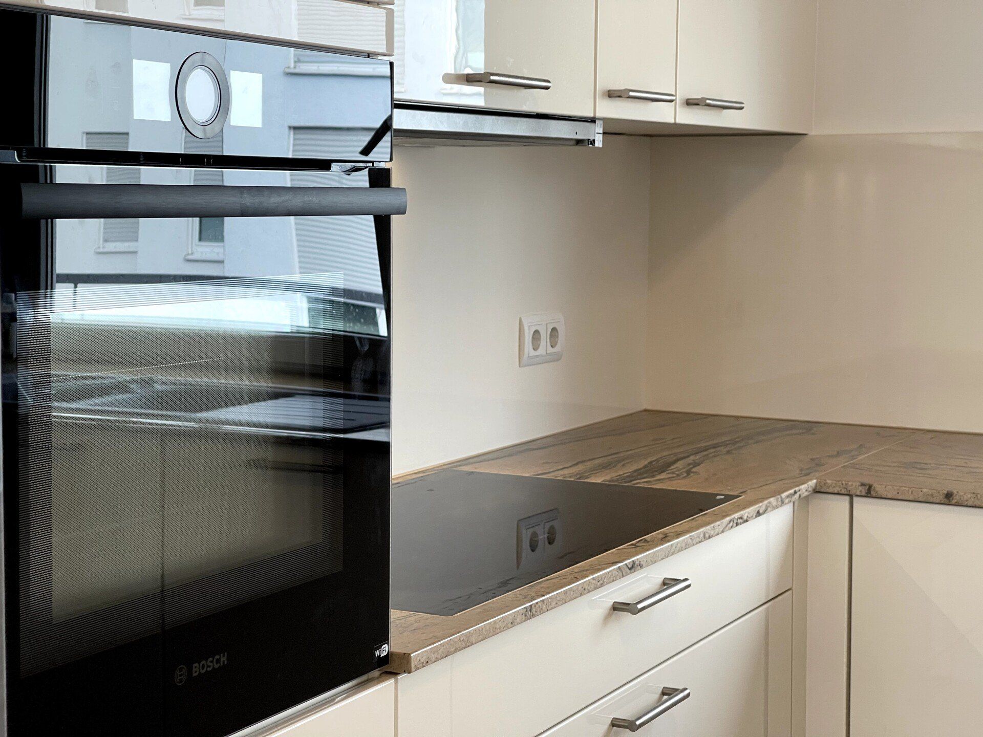 Verwandeln Sie Ihre Küche in einen Ort der Exzellenz und Ästhetik mit einer polierten Natursteinarbeitsplatte in Praha Gold und strahlenden Magnolia Hochglanzfronten. Die praktischen 2 Becken mit Abtropffläche und die fortschrittliche Vor-Fenster-Armatur von Blanco bieten Ihnen eine erstklassige Kochumgebung, die jeden Tag zum Genuss macht.