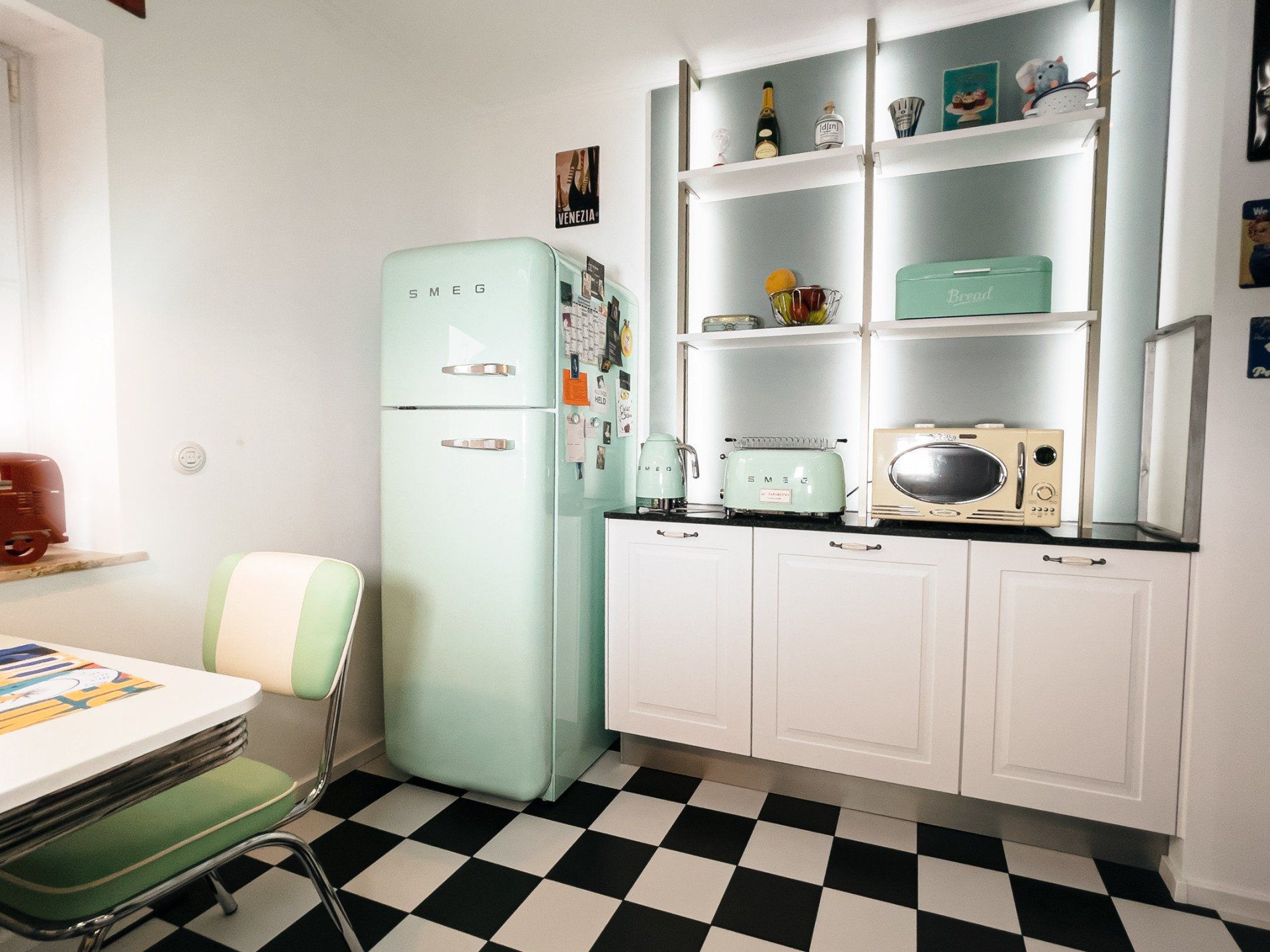 Tauchen Sie ein in die faszinierende Welt vergangener Epochen mit unserer Retro-Einbauküche. Die Kombination aus Smeg Einbaugeräten, einer kratzfesten Natursteinarbeitsplatte und den detailverliebten Fliesen im Schachbrettmuster schafft eine einzigartige Atmosphäre