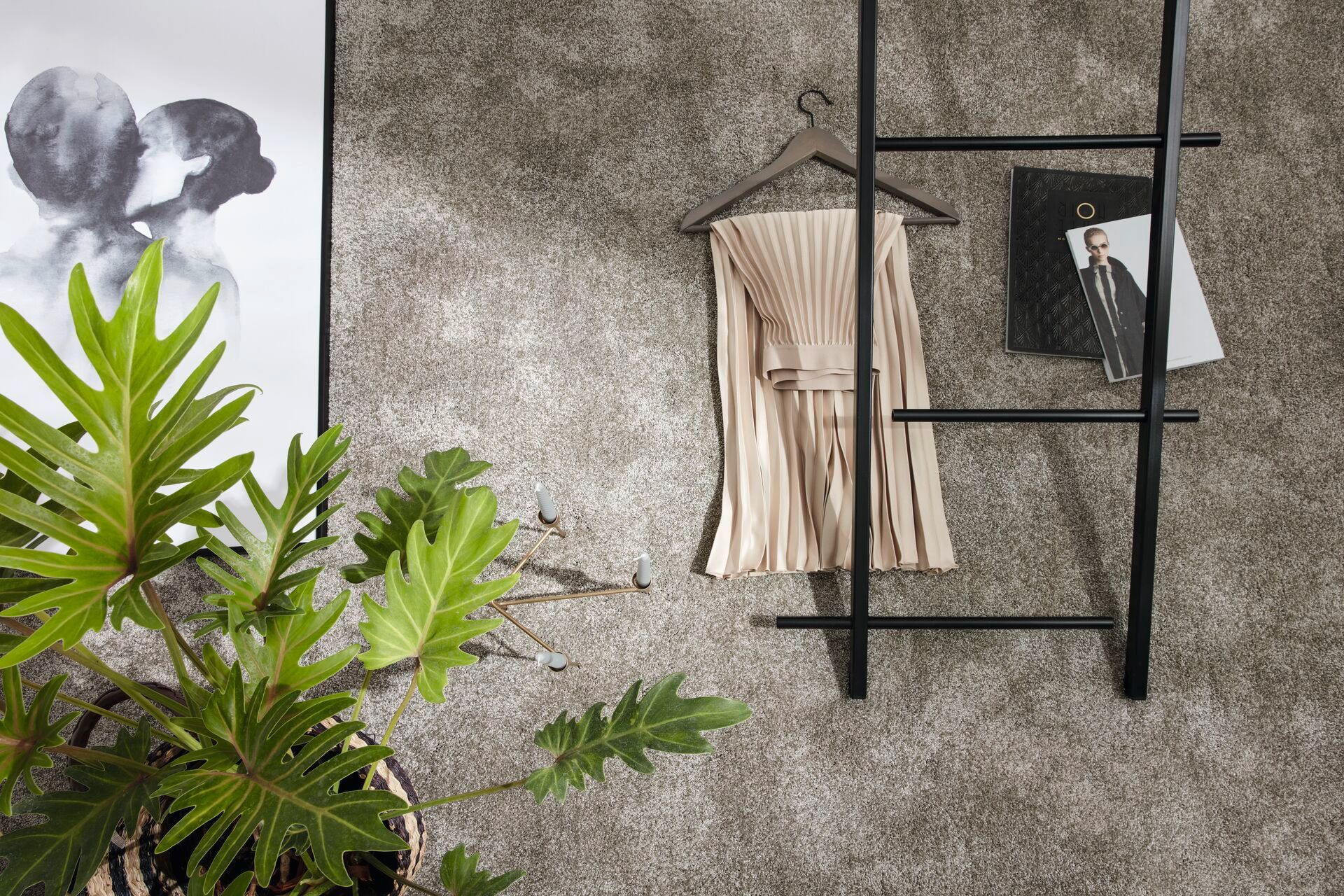 Weicher Teppichboden in Beige – moderne Inszenierung mit Kleiderständer, Blättern und Skizzen.