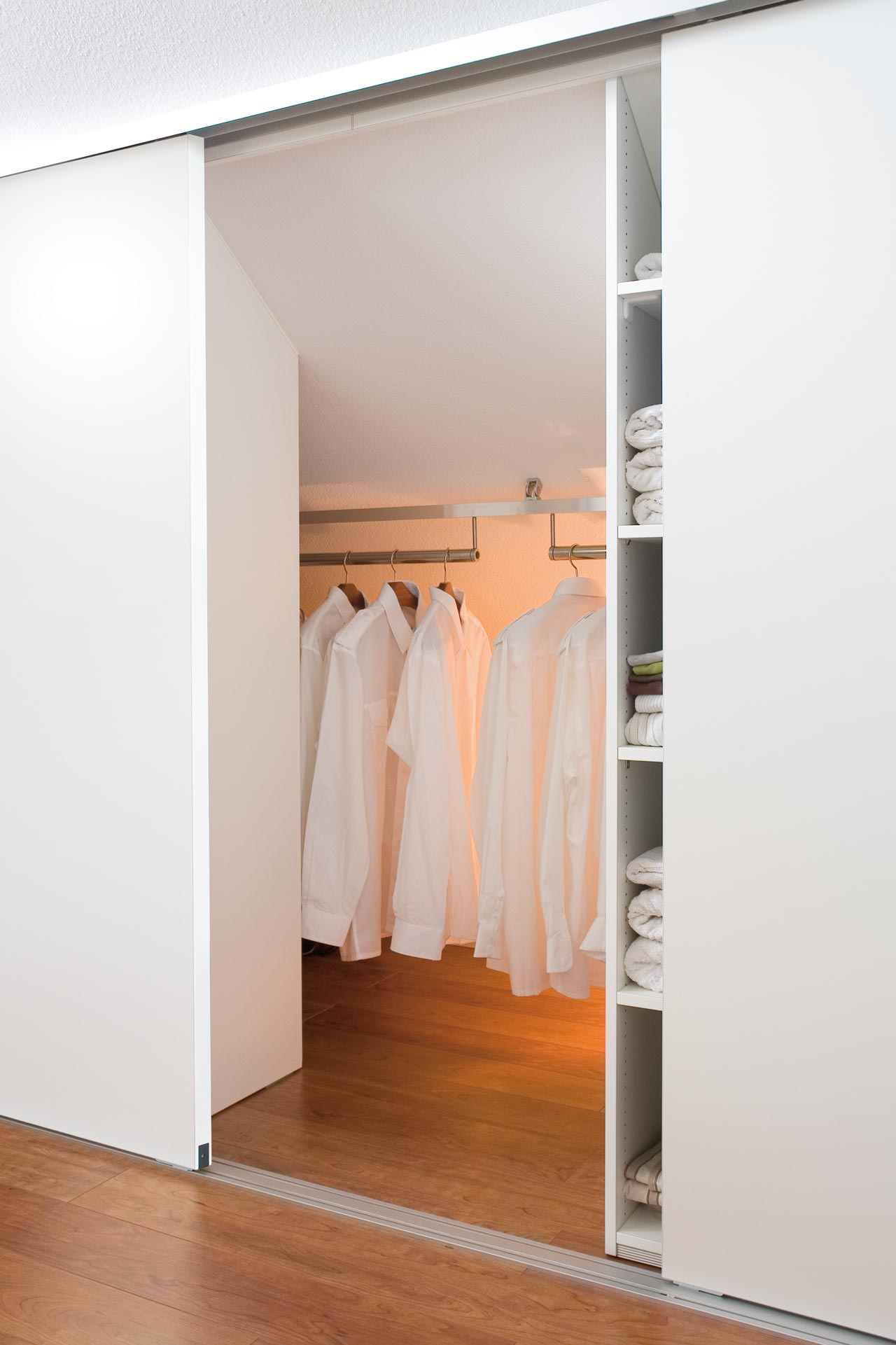 Der dressglider, die verschiebbare Kleiderstange, hinter einem Schrank unter einer Dachschräge Der dressglider, die verschiebbare Kleiderstange, hinter einem Schrank unter einer Dachschräge