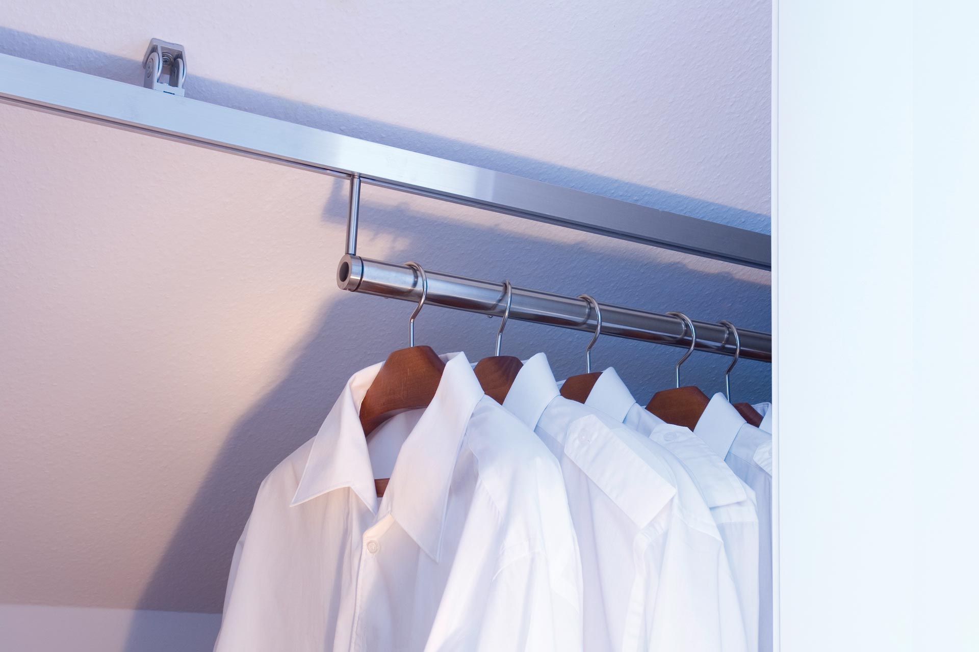 Der dressglider, die verschiebbare Kleiderstange, hinter einem Schrank unter einer Dachschräge Der dressglider, die verschiebbare Kleiderstange, hinter einem Schrank unter einer Dachschräge