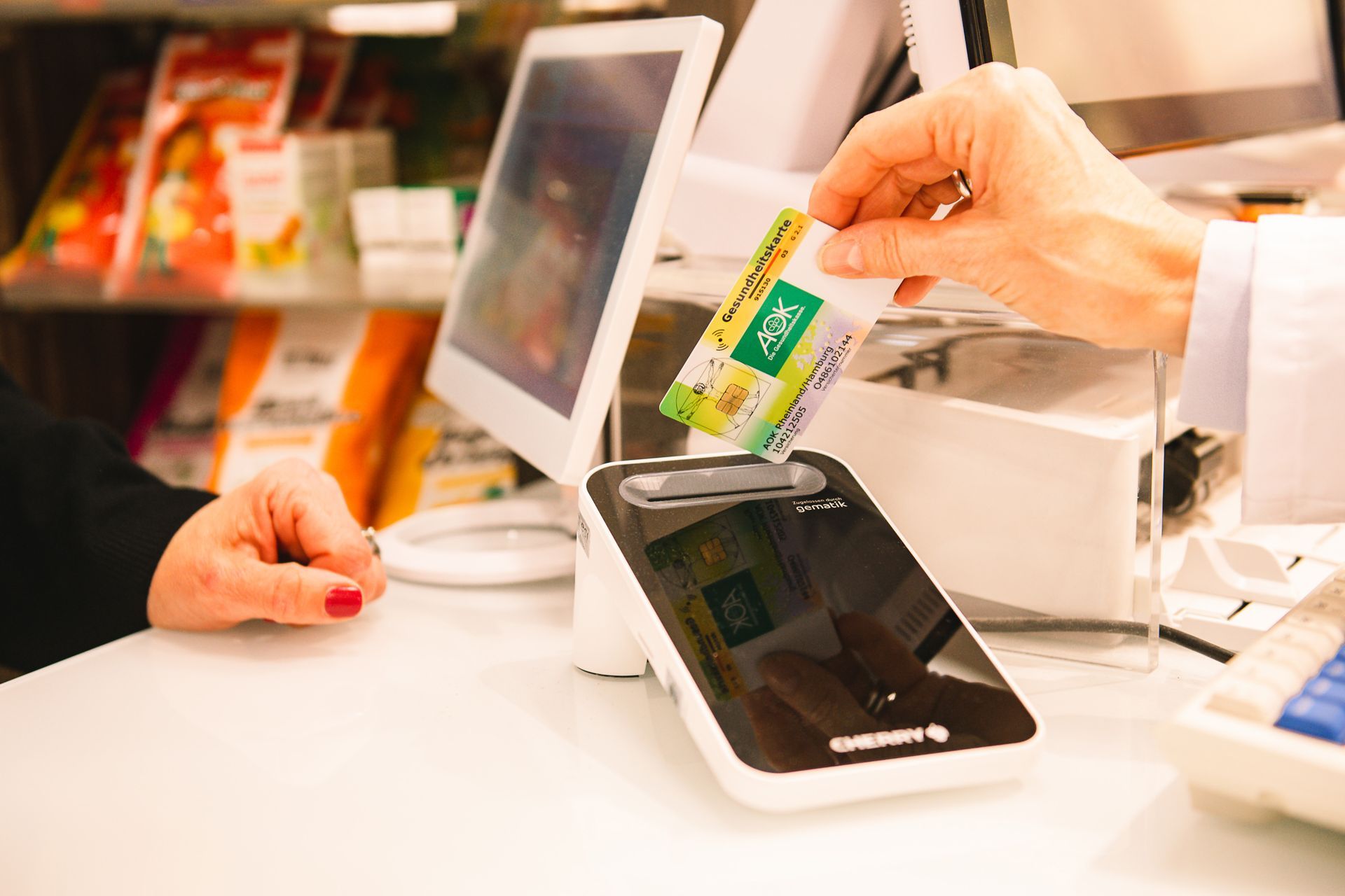 Kunde in Apotheke steckt die Krankekassenkarte in das Lesegeraet