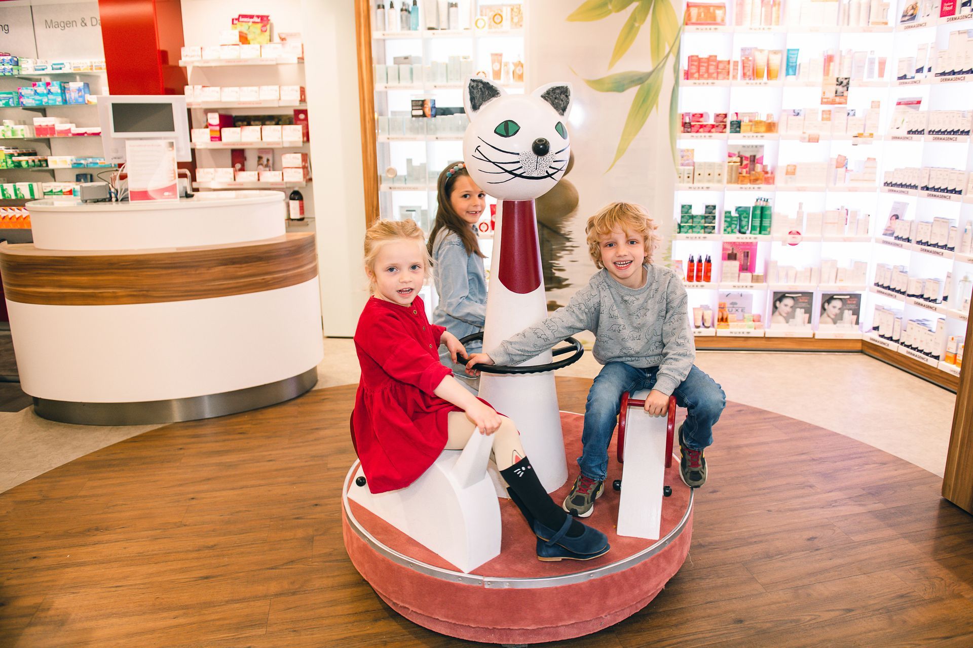 Apothekerin bedint eine Mutter mit zwei Kindern am Empfangstresen