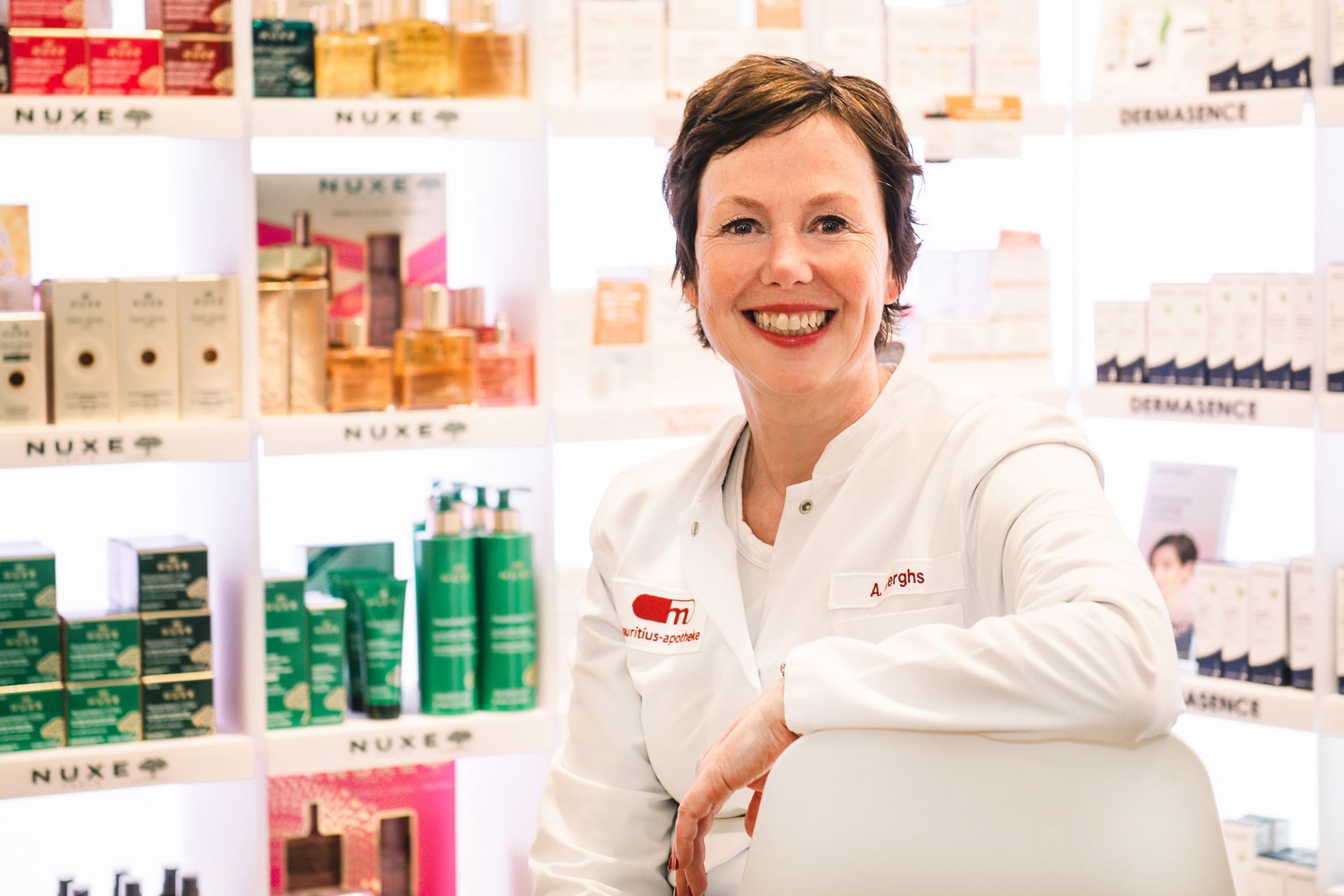 Apothekerin Almuth Berghs sitzend vor Kosmetikregal
