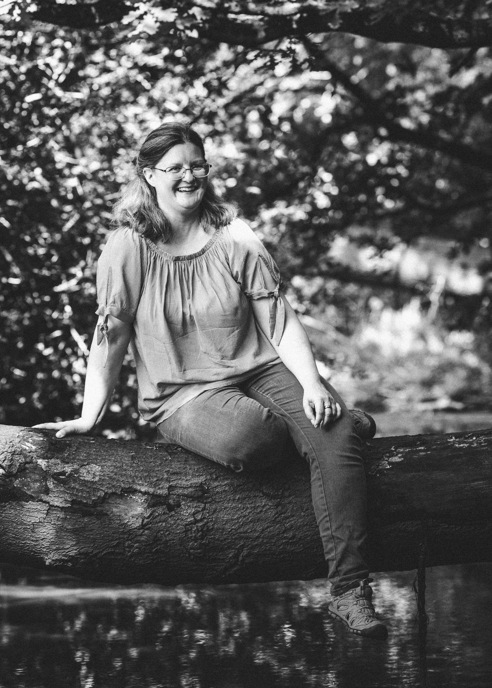 Autorin D. K. Berg sitzt auf einem Baumstamm