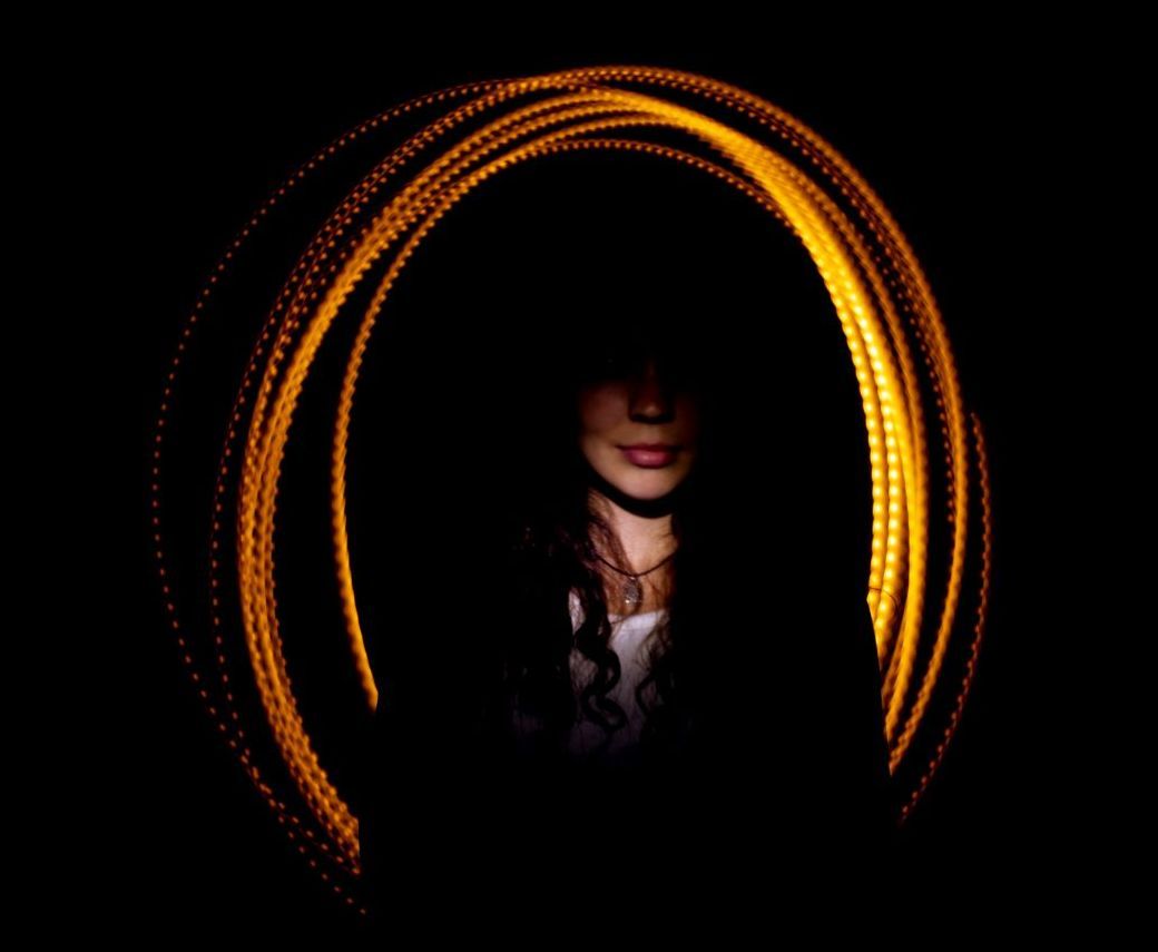 Eine Frau verschwindet in einem Lichtbogen vor einem schwarzen Hintergrund
