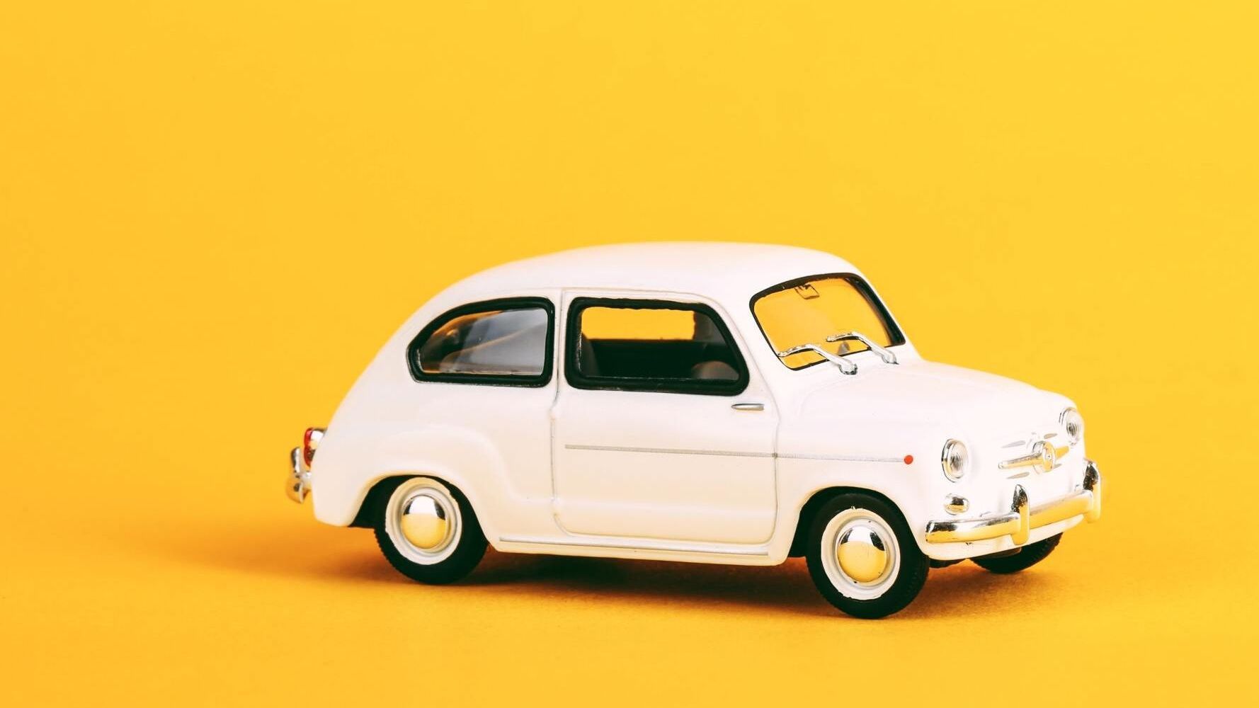 Weisses Miniatur-Auto auf gelbem Hintergrund Weisses Miniatur-Auto auf gelbem Hintergrund