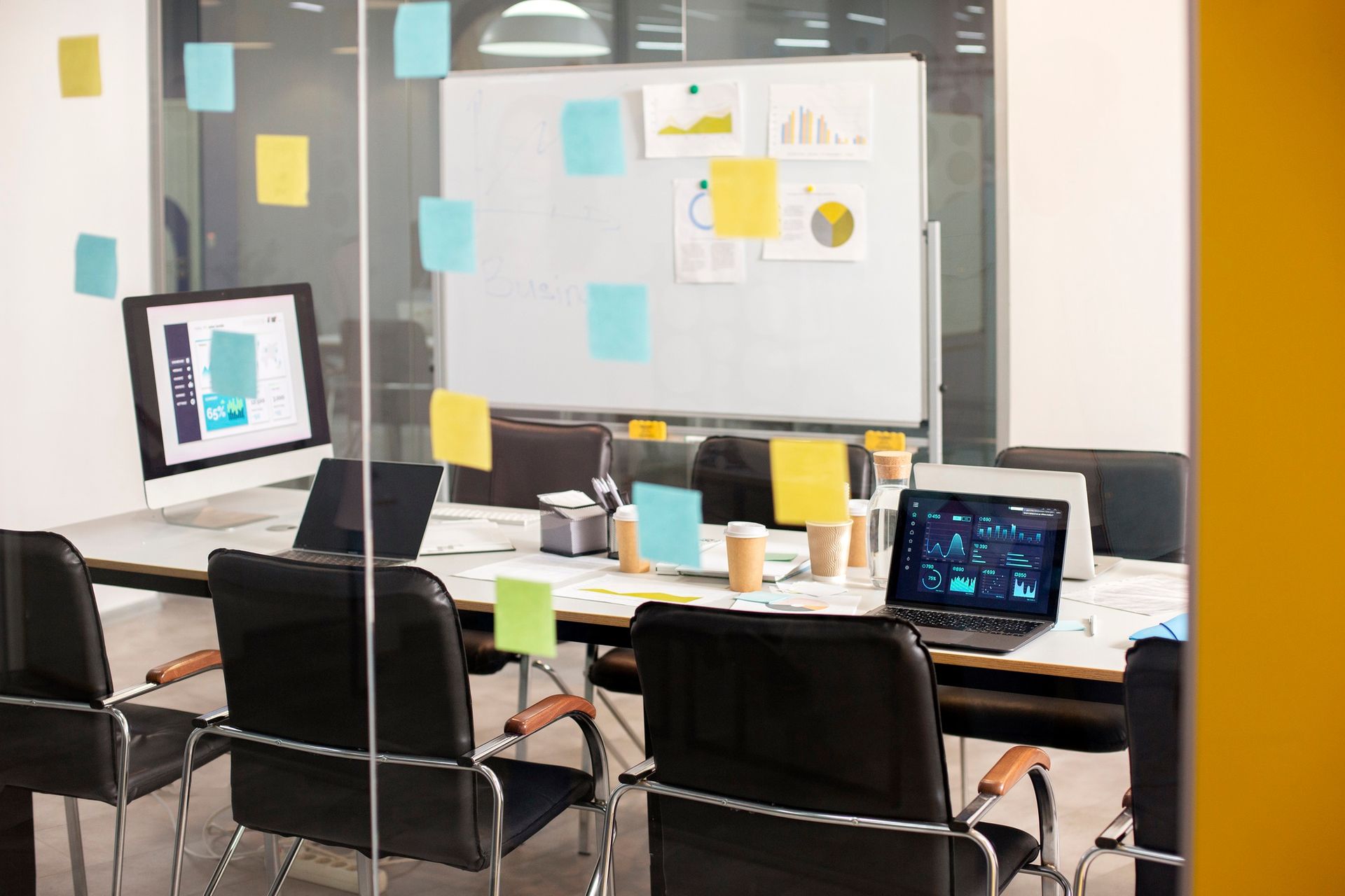 Sitzungsraum während Pause: Laptops, Whiteboard & Zettel an Glaswand deuten auf agile Prozesse