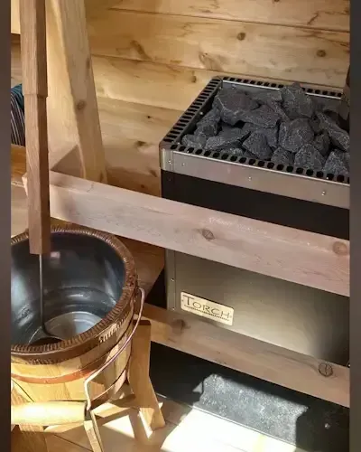 Sauna heater with a dipper of water ready for loyly