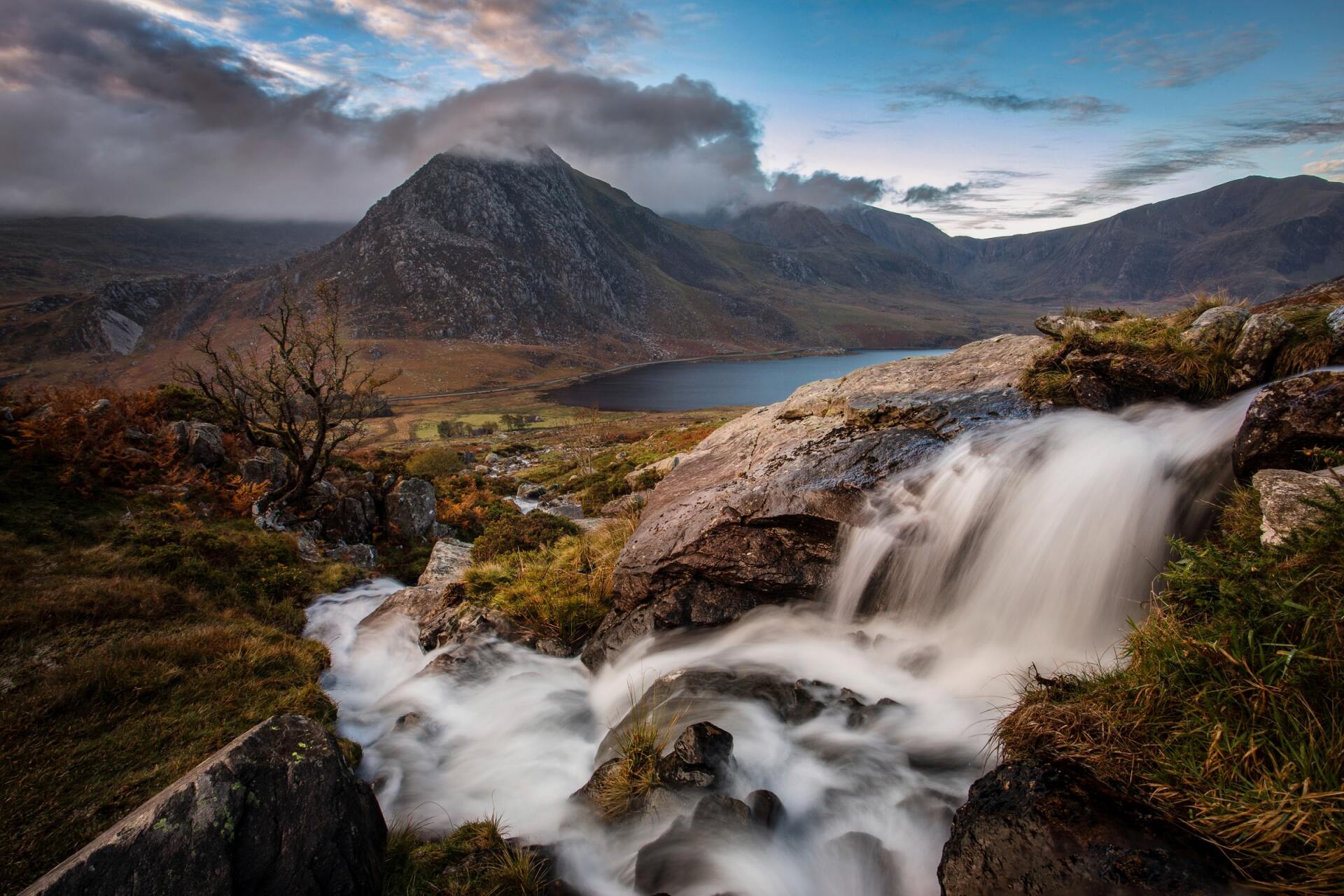 white water waterfall in mountain scene with lake in background