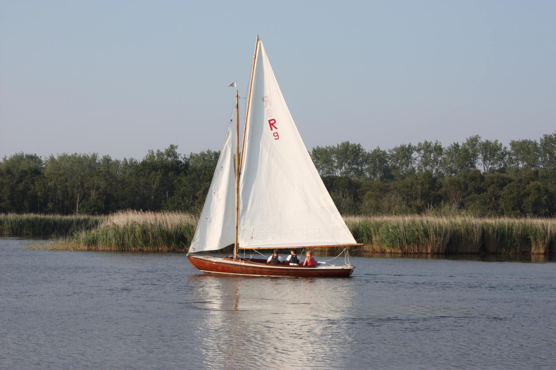 Boat with white sails on lake