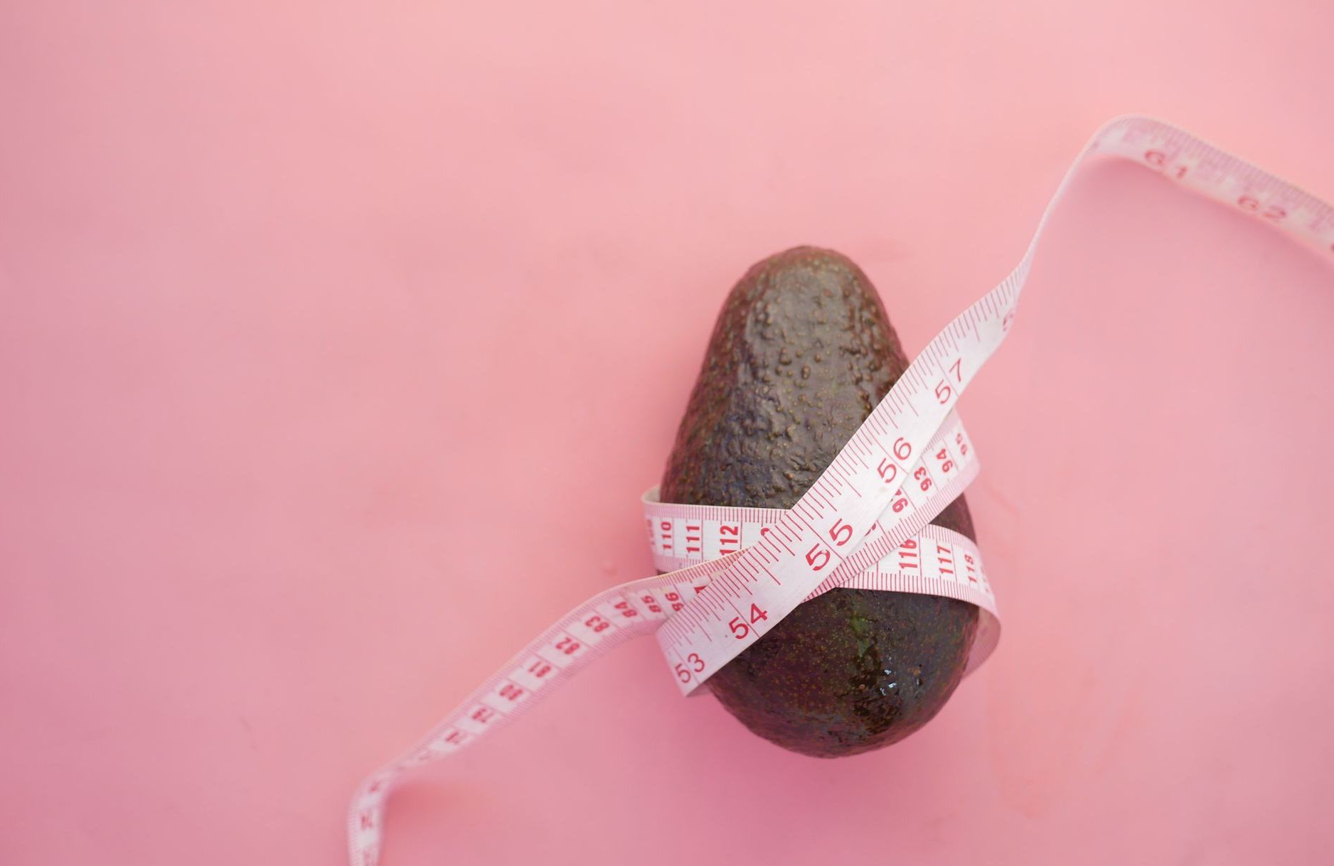 Avocado with a measure tape wrapped around it.