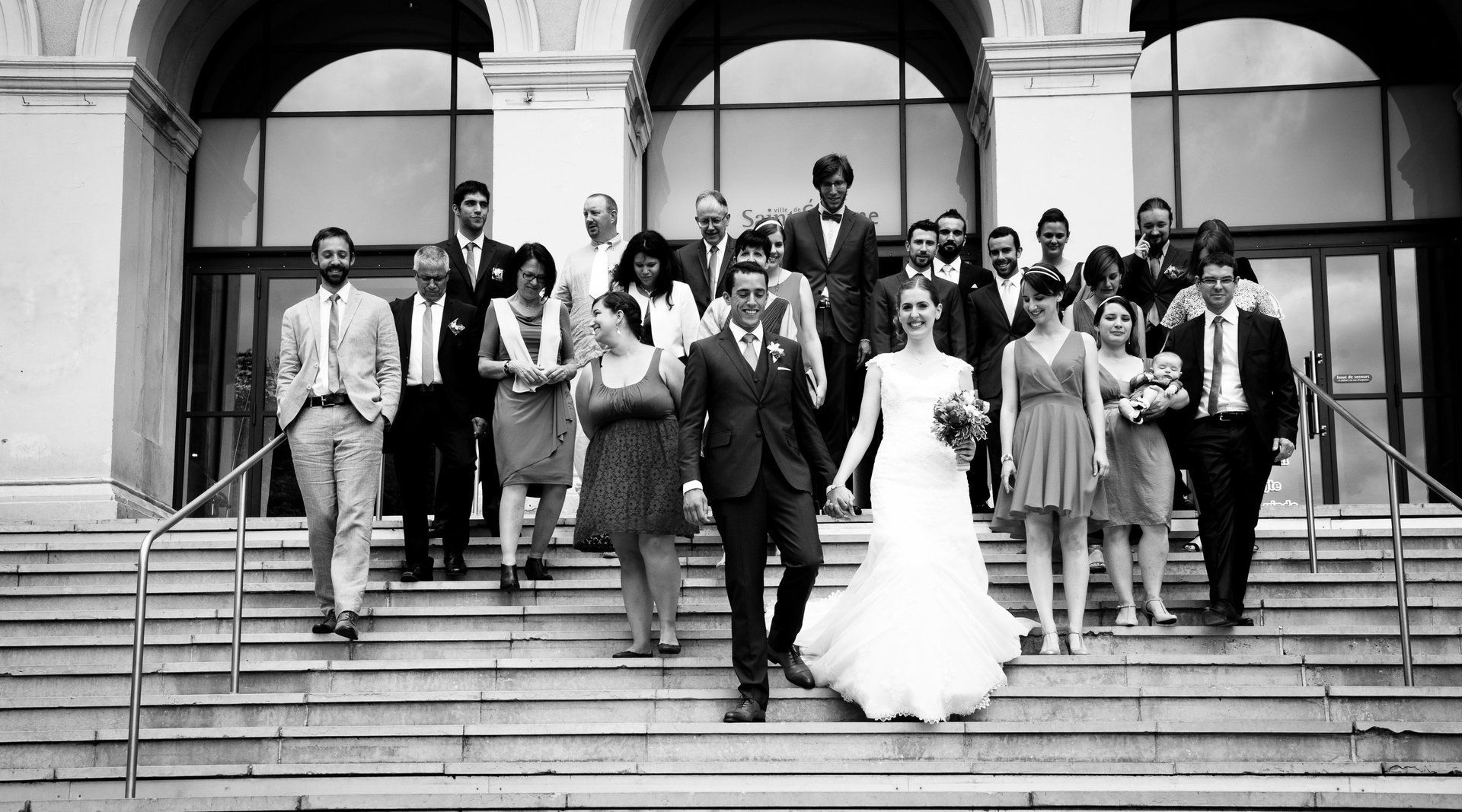 Photographie de mariage de Elizabeth Perrot Photo. Sortie de la mairie avec les invités du mariage. Mariage à Saint-Etienne, Loire, Rhône Alpes, France.
