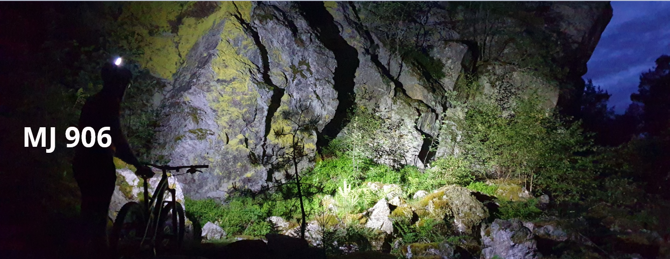 Magicshine LED Helmlampe MJ 906 mit 3200 Lumen, ein Mountainbike Fahrer strahlt mit seiner Helmlampe eine Seinwand extrem hell an im Wald