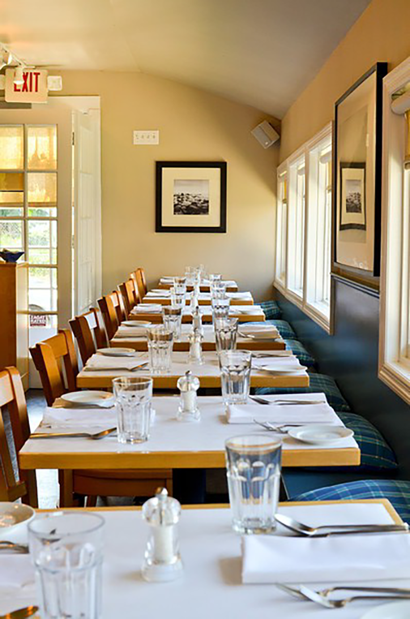Row of six tables for two, with silverware and water