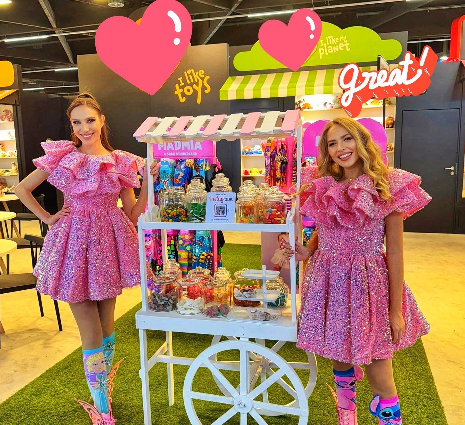 Models auf der Spielwarenmesse in Nürnberg in pinken Kleidern neben einer Candy Bar