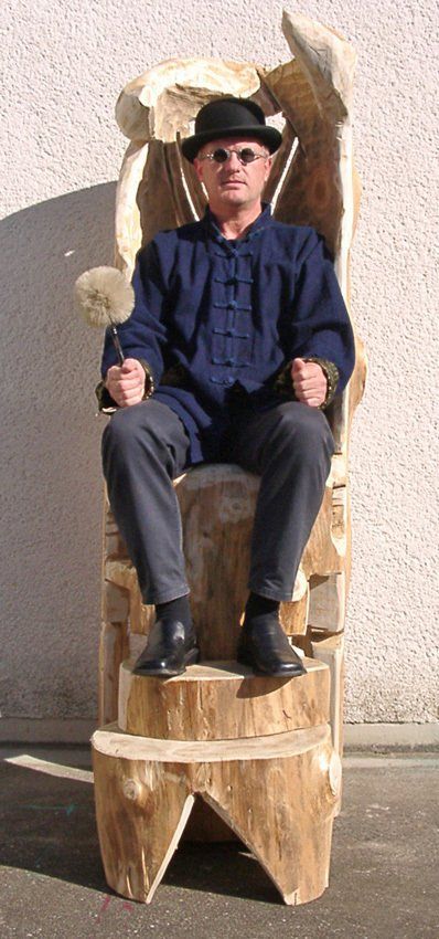 Mann mit Bowlerhut und Zepter auf hölzernem Thron