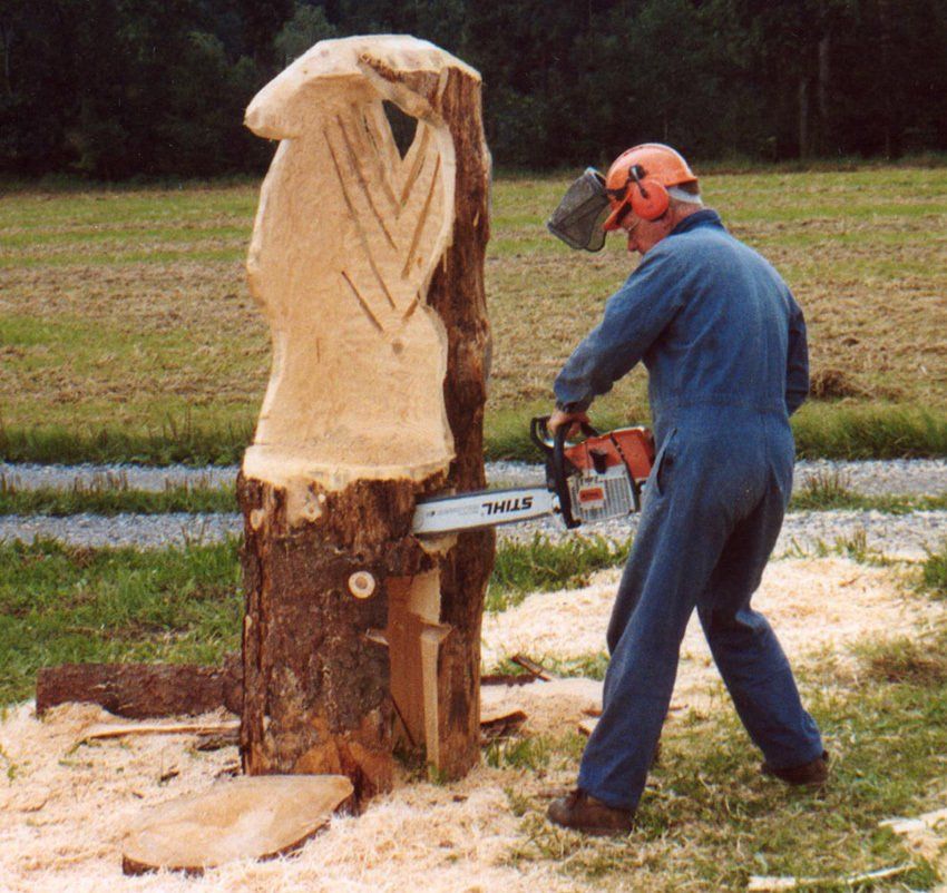 Mann mit Motorsäge arbeitet an einer Holzskulptur