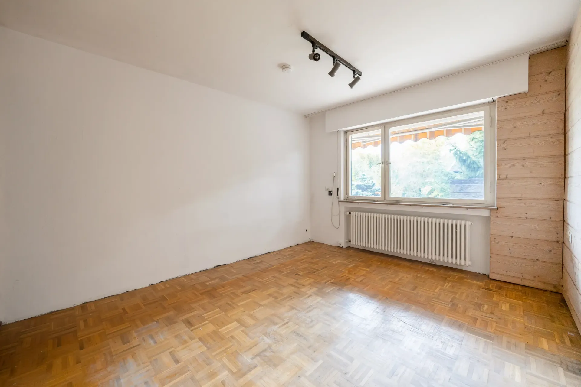 Helles Zimmer mit großem Fenster und Parkettboden