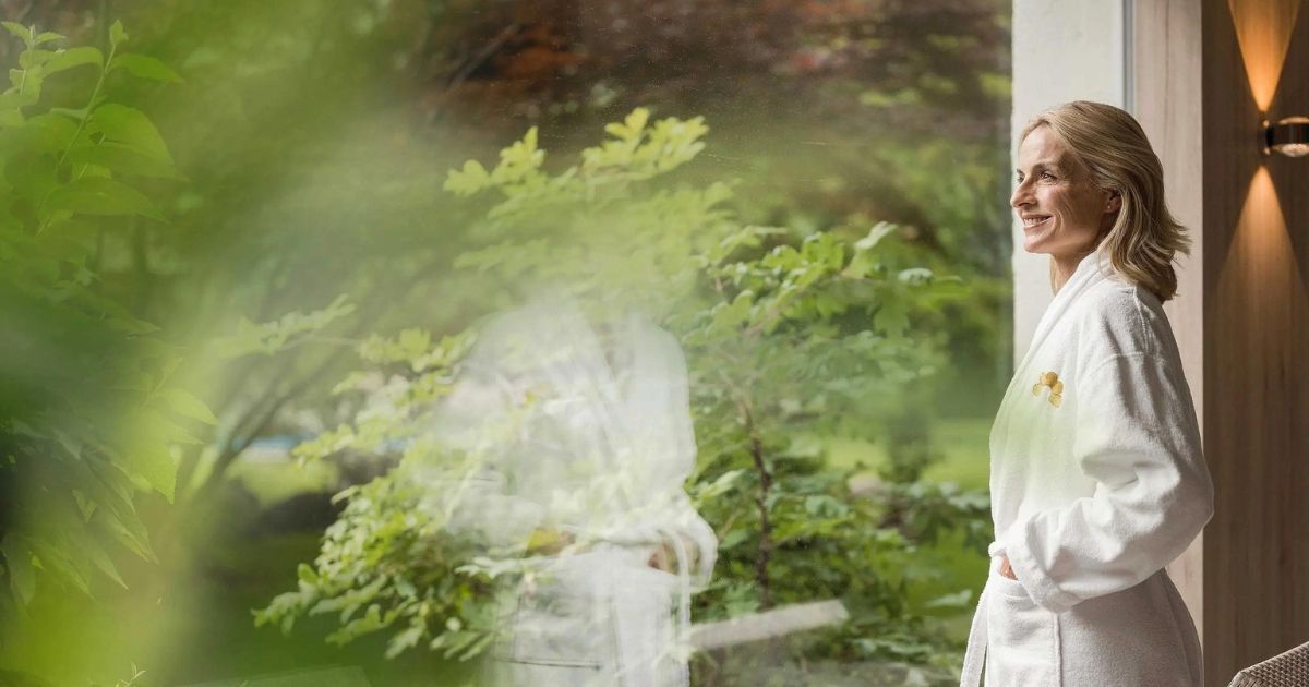 Donna in una spa che guarda un giardino in primavera
