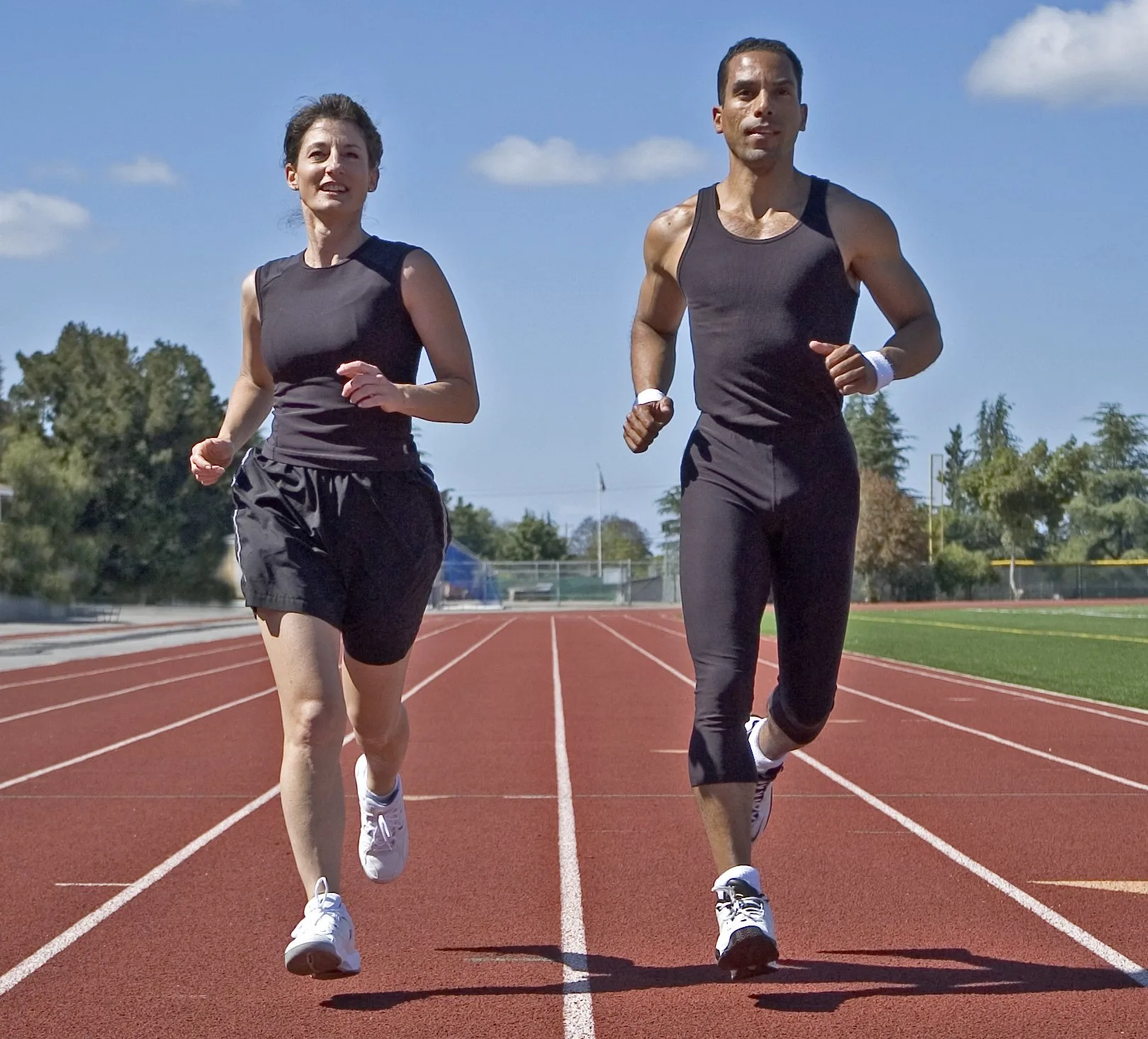 Zwei Personen laufen auf einer Laufbahn