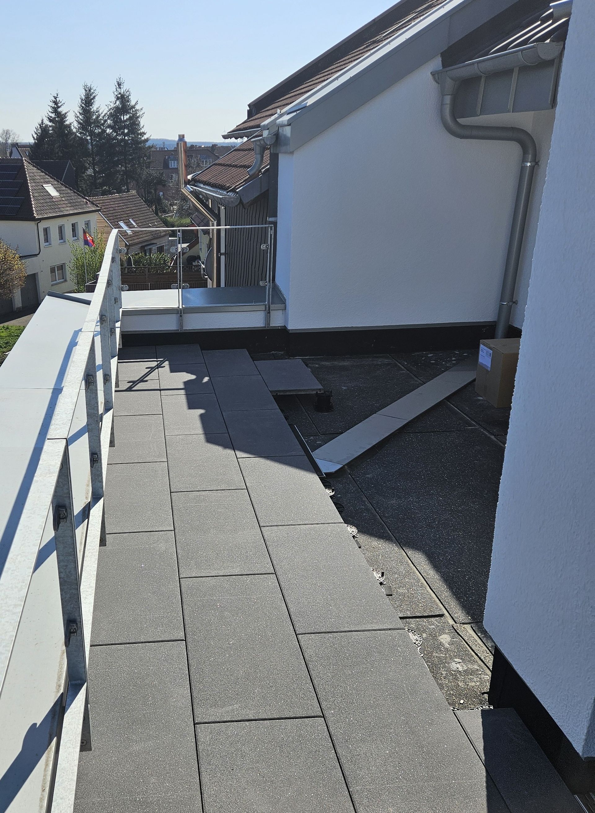 Flachdachterrassen mit Entwässerung, Plattenbelag und Glasbrüstung müssen gut geplant werden.