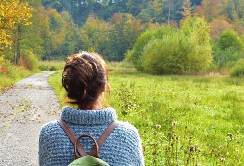 Gesundheitsziel verfolgen. Link zu Terminbuchung. Frau wandert auf harmonisch gewundenem Weg, wohlfühlen, Entspannung.