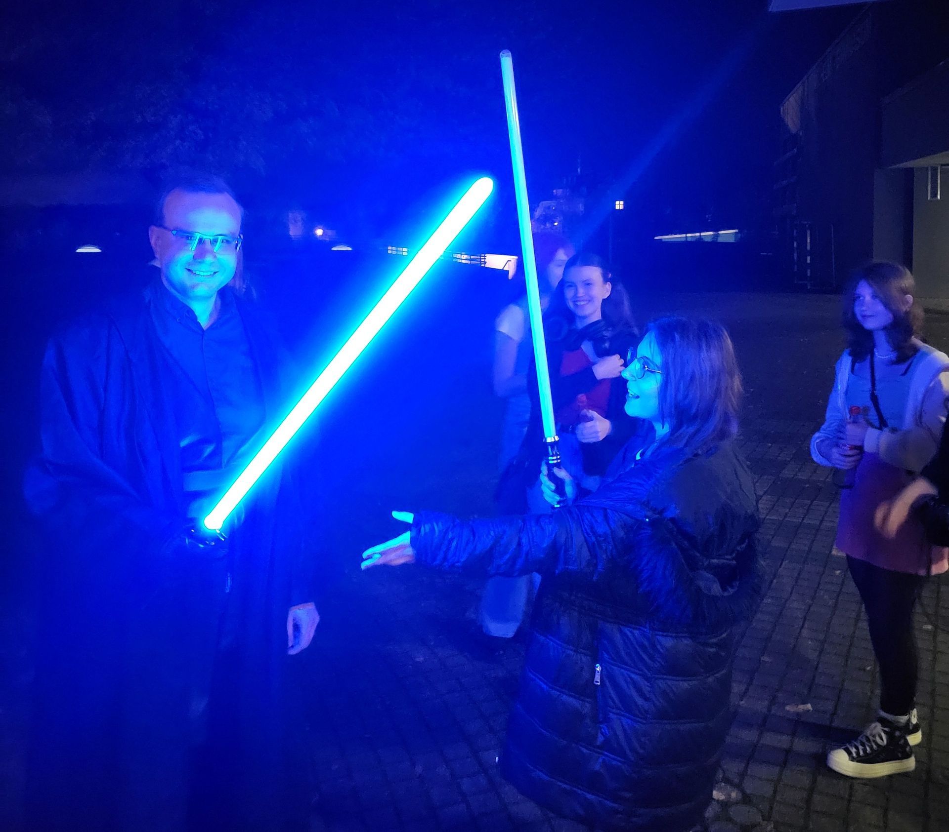 Lehrkraft und Schülerinnen beim Lichterschwert-Duell während der Halloween-Fete
