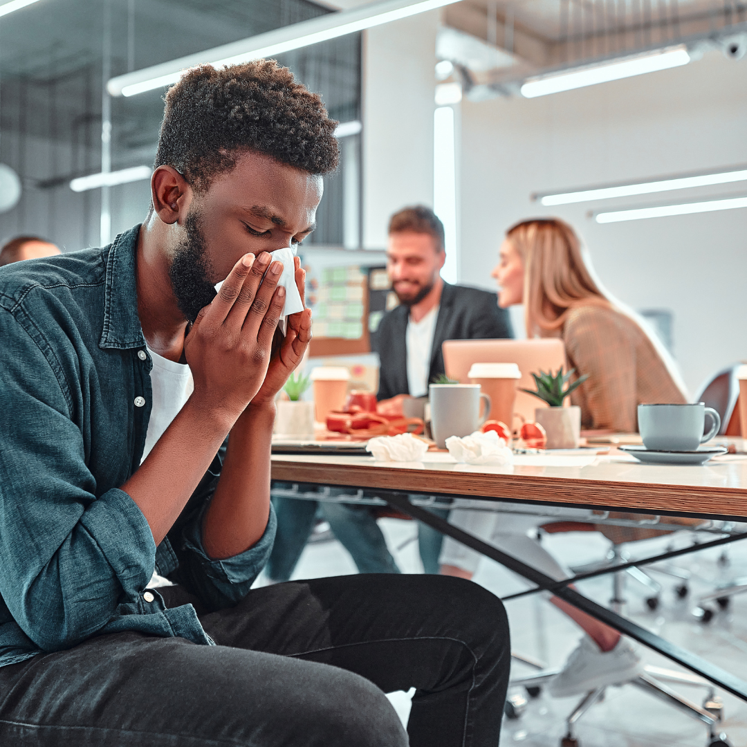 man in office blowing his nose