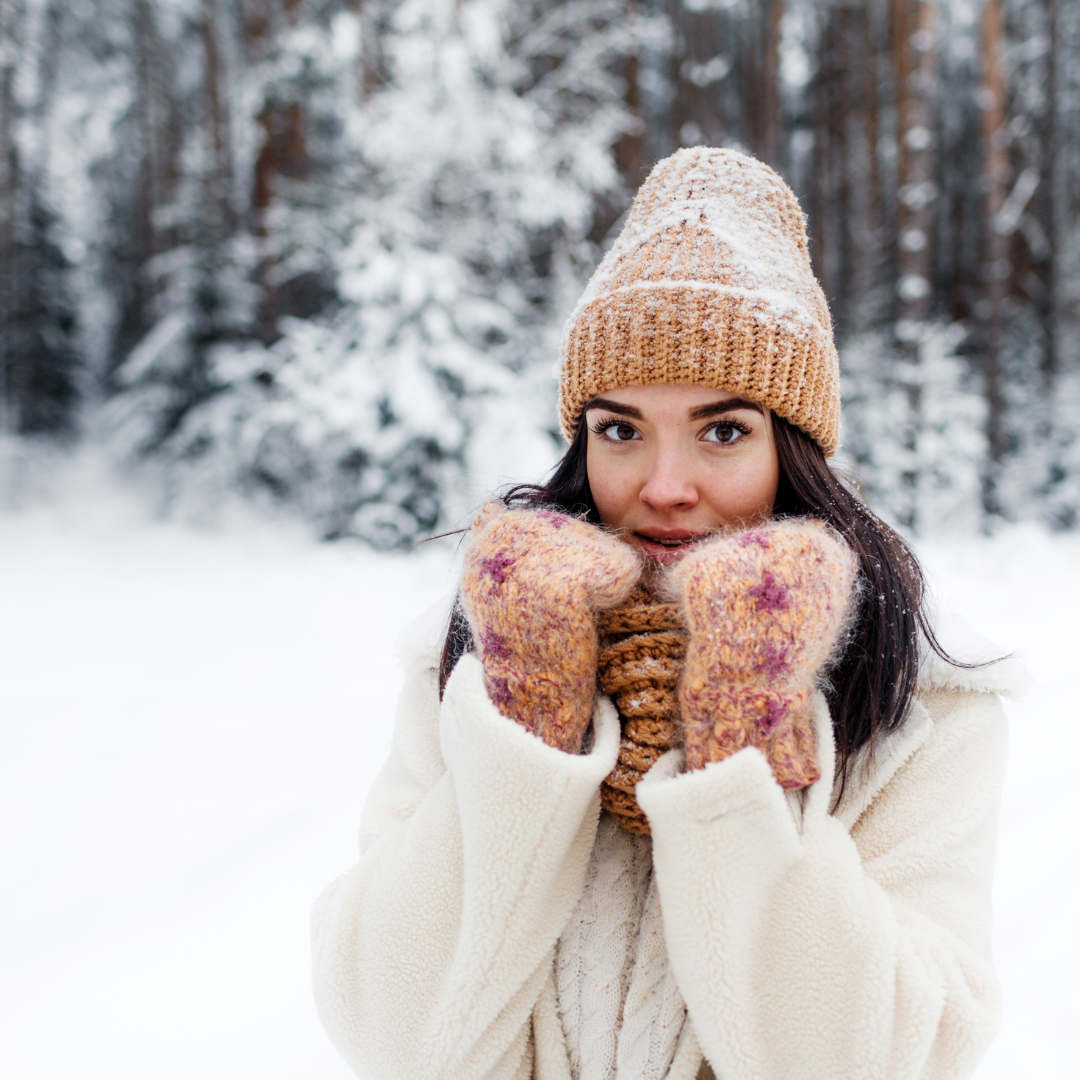woman in the snow with hat scarf and gloves on