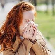 woman blowing nose outside