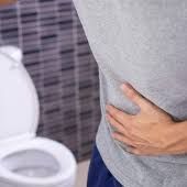 man holding belly next to toilet