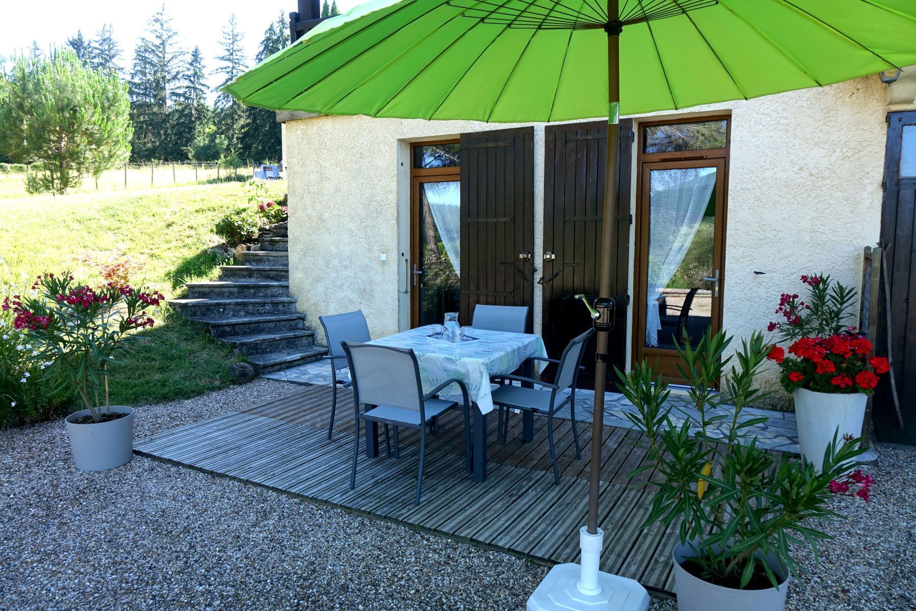 La casa rural (apartamento) vista de la terasa la sombrilla verde y la mesa cuadrada con las sillas