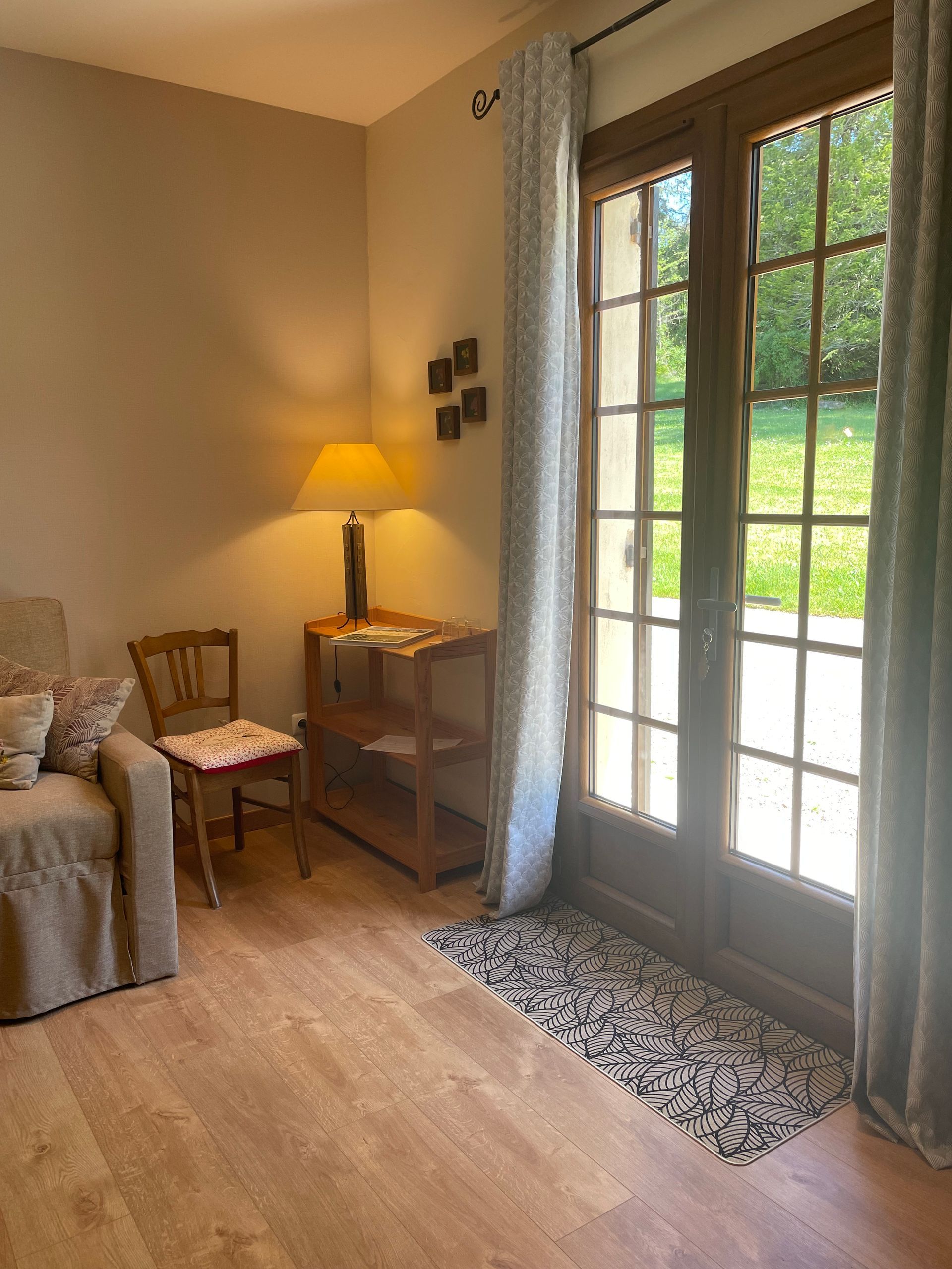 Vue sur le parc depuis l'entrée du salon. Lampe de chevet et décoration murale.