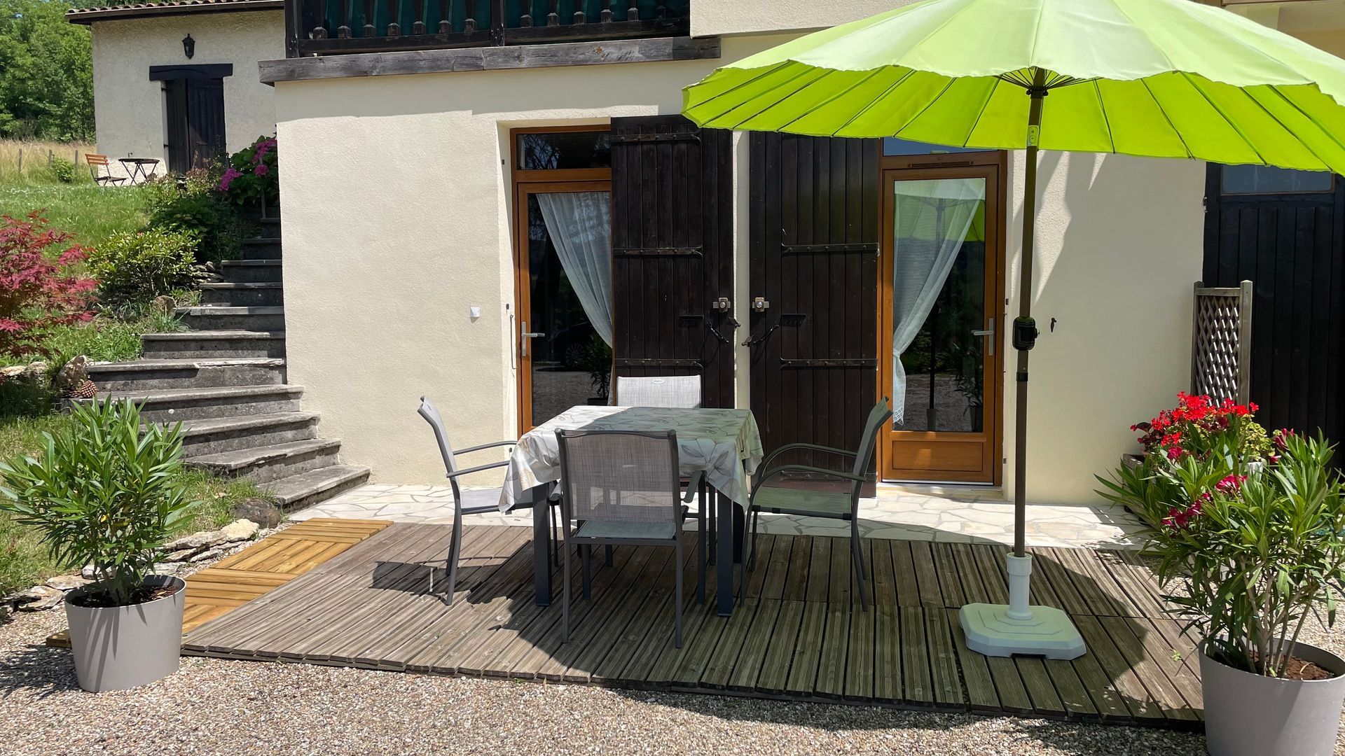 La casa rural (apartamento) vista de la terasa la sombrilla verde y la mesa cuadrada con las sillas