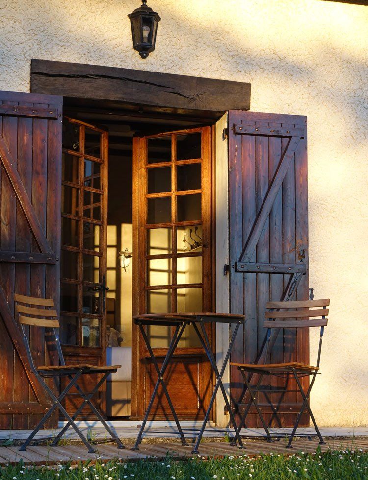 Vue extérieure chambre Sérénité, terrasse avec table et chaises en bois et fer forgé