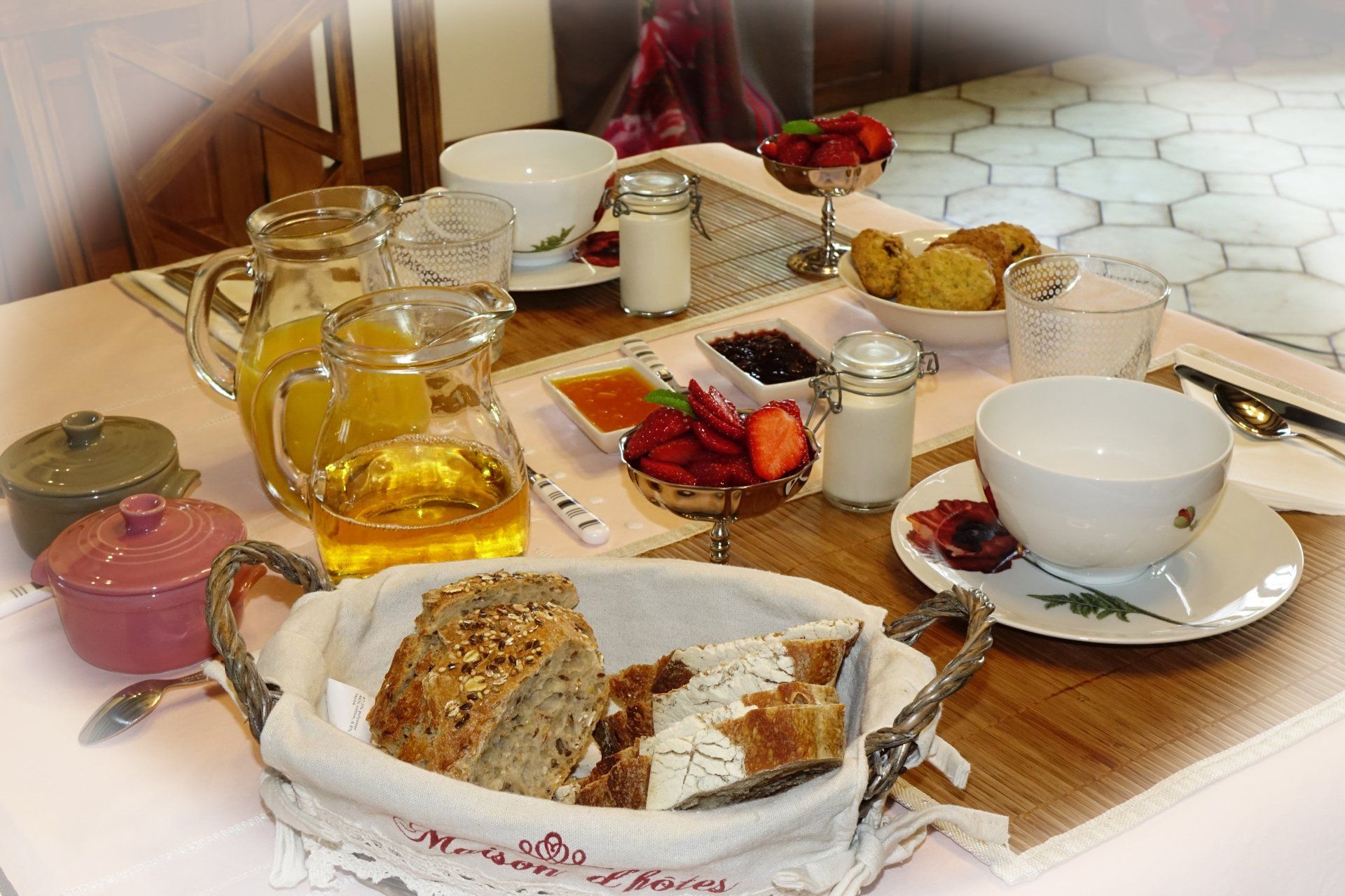 Petit-déjeuner avec tasses, verres, pains, yaourts, jus de fruits, confitures et pâtisseries faites maison, miel