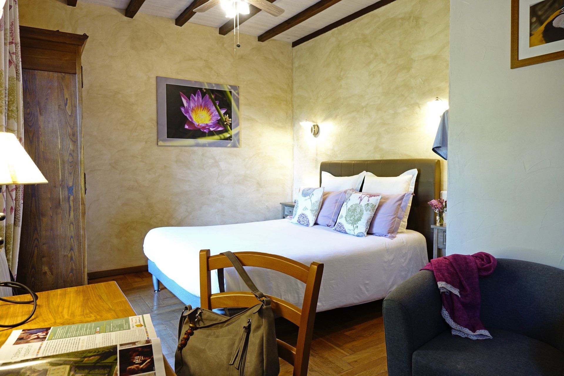 Vue intérieure chambre Sérénité, chaise et fauteuil au premier plan. Lit et photos murales.