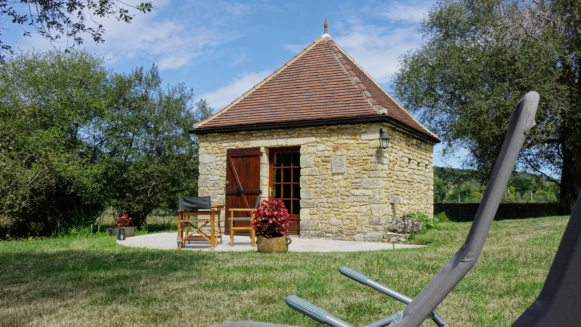 Vue de La Borie (petite maison en pierres) avec sa terrasse et les transats au premier plan