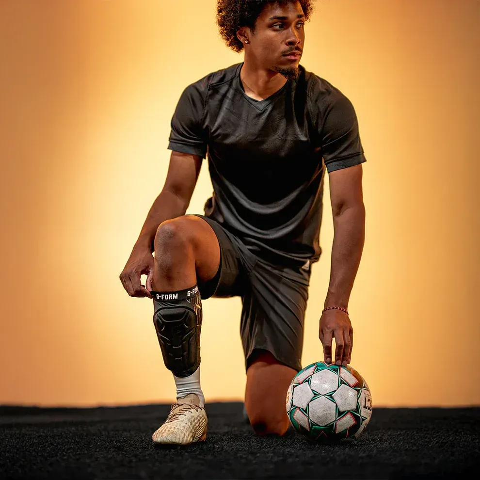 Soccer player wearing a knee pad, kneeling with a soccer ball