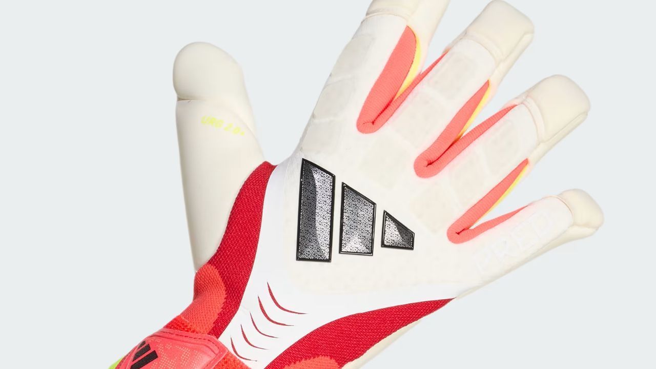 Adidas goalkeeper glove with white latex palm and red wrist strap.