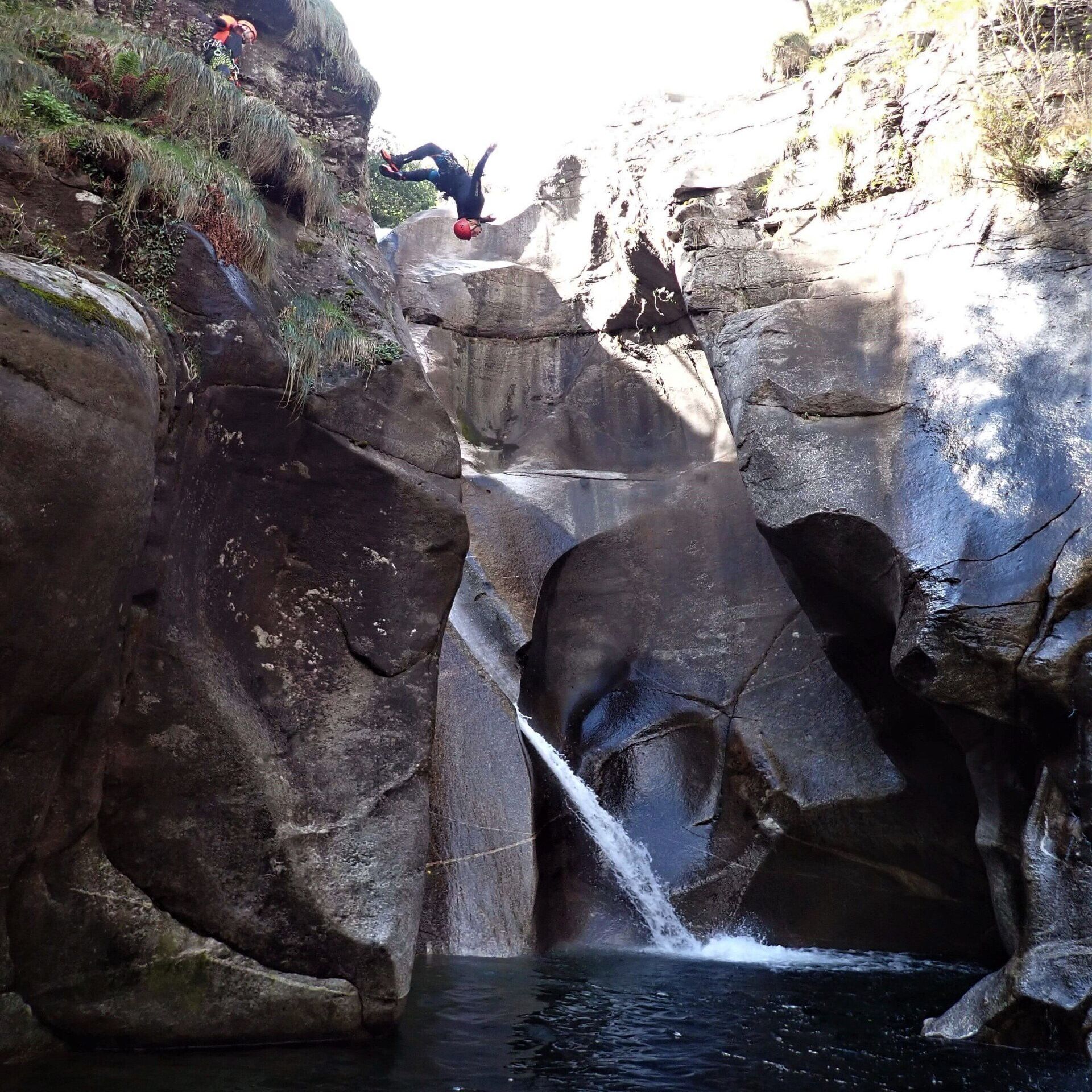 Ein Canyoning-Guide im Tessin macht einen Backflip von einem Felsen in der Schlucht Iragna
