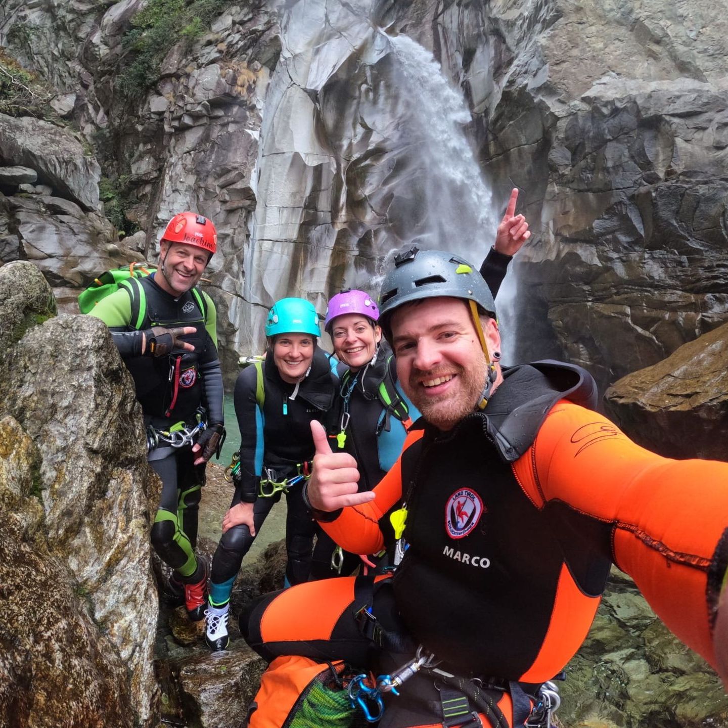 Eine Gruppe von Canyoning-Guides von Blue-River-Canyoning vor einem Wasserfall im Tessin
