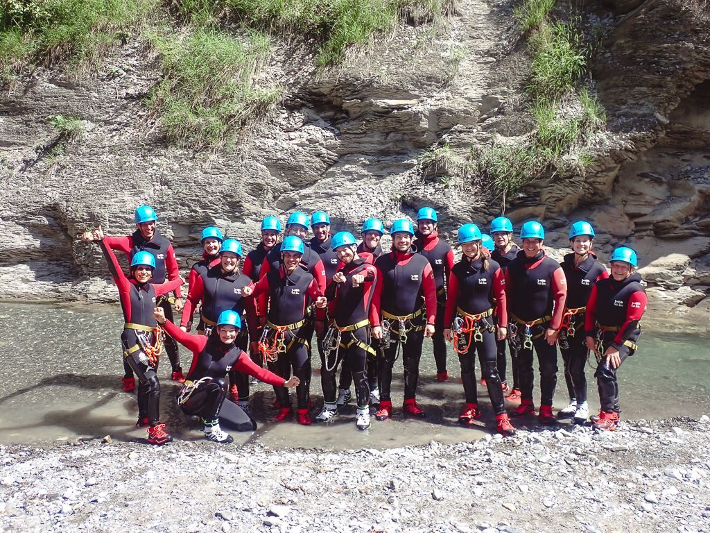 Große Canyoninggruppe in voller Ausrüstung am Einstieg der Kobelach nach der Sicherheitseinweisung, versammelt am Ufer vor der Schlucht.