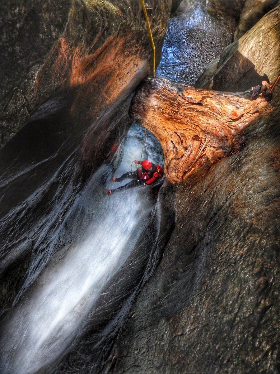 Ein Canyoning-Guide seilt in der Rudach-Schlucht an einem Baumstumpf vorbei