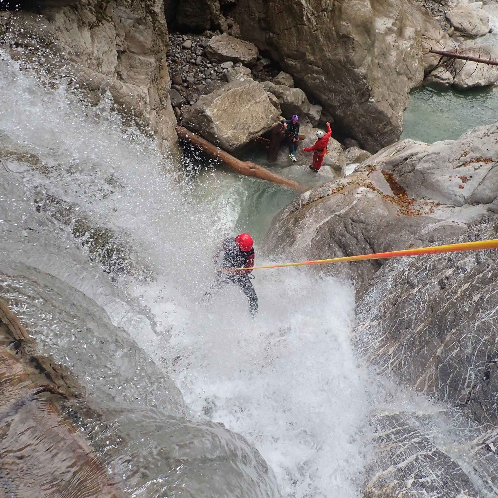 Ein Canyoning-Gast seilt sich durch einen Wasserfall in Vorarlberg ab